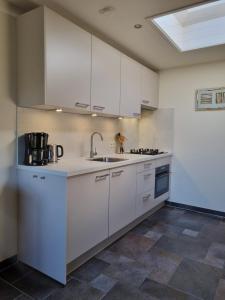 a kitchen with white cabinets and a sink at Mooi zo 2 in De Koog +12 photos