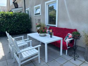ein weißer Tisch mit Stühlen und ein rotes Sofa auf einer Terrasse in der Unterkunft Kullsbacka in Skanör med Falsterbo