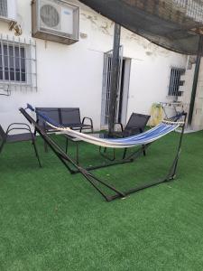 a hammock on a patio with chairs on the grass at Casa adosada con patio in Jerez