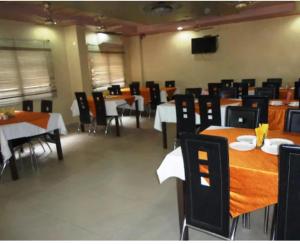 a dining room with tables and chairs and a television at hotel darbar international in Gaya