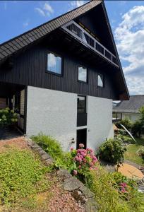 a black and white house with flowers in front of it at Stadtvilla Annabelle - mit Sauna in Meschede