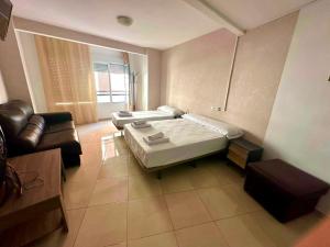 a room with two beds and a couch at Hostal Alegria Alicante in Alicante