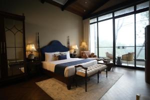 a bedroom with a bed and a chair and windows at Van Rāsa in Kasauli