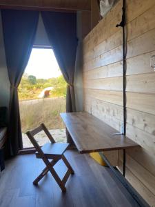 a wooden table and a chair in a room with a window at Tiny ou Petite maison sur roulettes in Le Fay