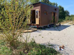 a brown tiny house sitting on a gravel lot at Tiny ou Petite maison sur roulettes in Le Fay