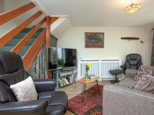 a living room with a couch and a flat screen tv at Garden Cottage in Kingsbridge