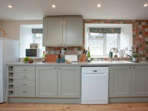 a kitchen with white cabinets and a white dishwasher at Garden Cottage in Kingsbridge +11 photos