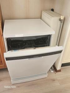 a white dishwasher in a kitchen next to a refrigerator at De Weerribben Wieden, Natuurhuisje in Wanneperveen