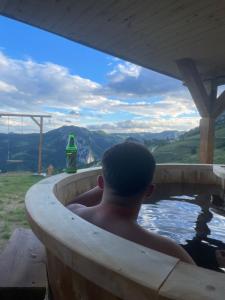 a man in a hot tub looking out at the mountains at Cabana AxD in Cotorăşti