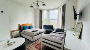 a bedroom with a bed and a chair and a table at Spacious Triple Studio Room, Private En-Suite & Kitchenette R6 in Sketty +3 photos