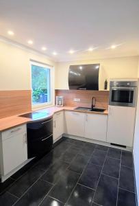 a kitchen with white cabinets and a black tile floor at Lavendelhaus am Müritzsee - direkt am Wasser in Buchholz +10 photos