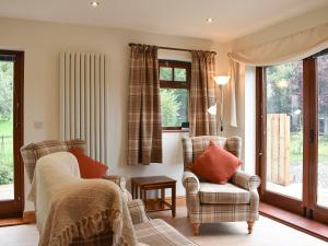 a living room with two chairs and windows at Brooklands Cottage in Bellerby