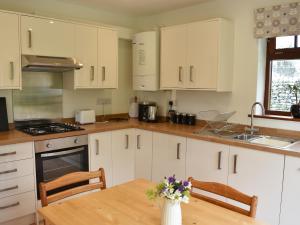 a kitchen with white cabinets and a wooden table at Brooklands Cottage in Bellerby