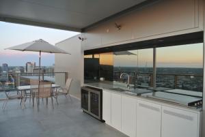 a kitchen with a table and a view of the city at VUE Penthouse on King William in Adelaide