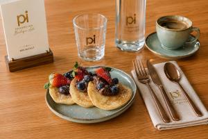 a plate of pancakes with strawberries and berries on a table at Hotel PI Arte Exclusive Suite in Palermo