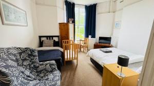 a small bedroom with a bed and a couch at Spacious Triple Studio Room, Private En-Suite & Kitchenette R6 in Sketty