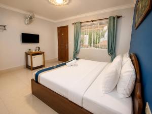 a bedroom with a large white bed with a window at Abode Hotel Siem Reap in Phum Pobos