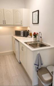a kitchen with white cabinets and a sink at Cosy apartment - Na Creagáin in Tully