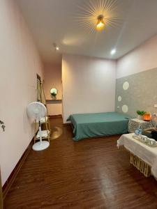 a bedroom with a green bed and a fan at BalaHomestay BalaHouse in Lạc Thành