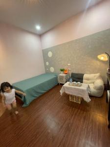 a little girl in a room with a bed and a couch at BalaHomestay BalaHouse in Lạc Thành +22 photos