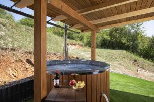 a hot tub under a wooden pergola with a bottle of wine at Villa Velebita House for 9 near Plitvice Lakes in Rudopolje