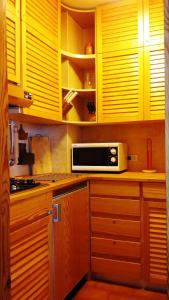 a kitchen with yellow cabinets and a microwave at CinqueSensi - Condominio La Zoca in Madesimo