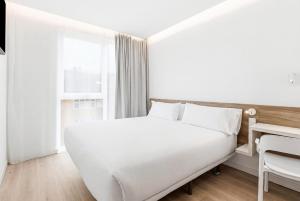 a white bedroom with a white bed and a desk at B&B HOTEL A Coruña Aeropuerto in Culleredo