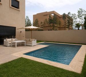 a swimming pool with chairs and an umbrella next to a house at Villa Émeraude in Marrakesh