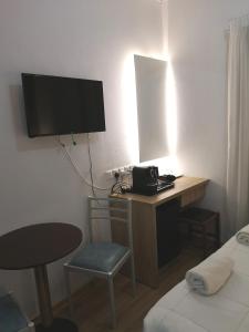 ein Zimmer mit Schreibtisch, Fernseher und Bett in der Unterkunft Ekali Hotel in Kakopetria