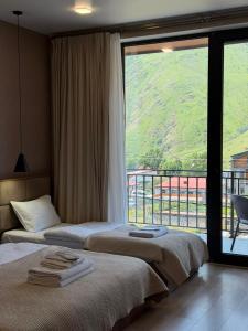 a hotel room with two beds and a large window at Hotel Sweet Night in Kazbegi