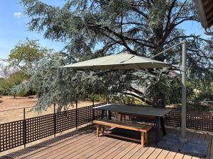 a picnic table with an umbrella on a deck at Cedar house in La Charité-sur-Loire