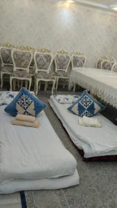 two beds sitting in a room with tables and chairs at Akmuz House in Ak-Muz