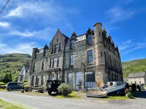 an old house with cars parked in front of it at Stunning Hideaway on Loch Goil in Carrick