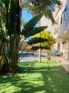 a green yard with palm trees and a building at Pousada Legno Bossa Nova in Maceió