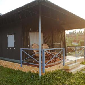 a black tent with two chairs on a porch at Birds Murmur Camp in Kotamangalam