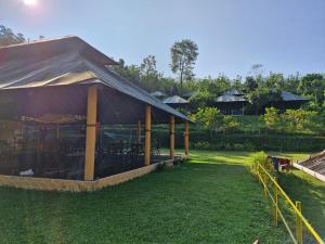 a building with a tent in the grass at Birds Murmur Camp in Kotamangalam