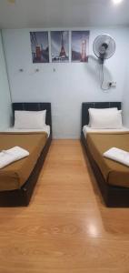 a room with two beds and a fan on the wall at SC Lodging Sinsuran Complex in Kota Kinabalu