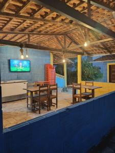 a patio with tables and chairs and a tv at Recanto Das Marés in Jacumã