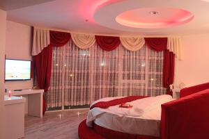 a bedroom with a bed and a large window with red curtains at Grand Beyaz Saray Otel in Duzce