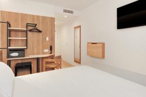 a bedroom with a bed and a tv on a wall at B&B HOTEL Madrid San Fermin in Madrid