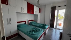 two beds in a room with red and white cabinets at David’s apartments in Hamallë