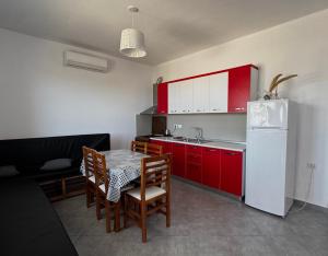 a kitchen with red cabinets and a table and a white refrigerator at David’s apartments in Hamallë
