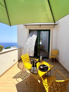 a yellow table and chairs on a balcony with a green umbrella at Las Palomas in Santa Flavia