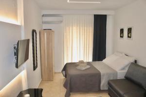 a bedroom with a bed and a couch and a television at Dany's studio central xanthi in Xanthi