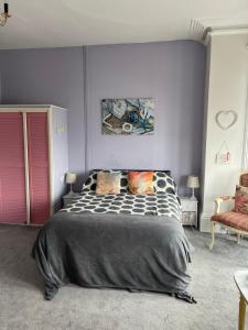 a bedroom with a large bed with a purple wall at Henry's On The Prom in Great Yarmouth