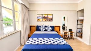 a bedroom with a blue and white bed and a desk at Flat Premium a 500m do aeroporto Santos Dumont & Consulados in Rio de Janeiro
