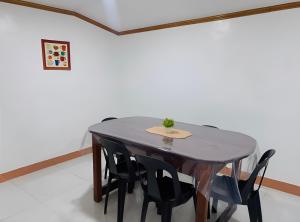 a table and chairs in a room with a white wall at Queen's Guest House in El Nido
