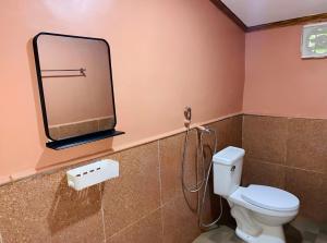 a bathroom with a toilet and a mirror on the wall at Queen's Guest House in El Nido