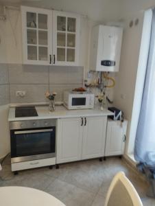 a kitchen with white cabinets and a microwave at Solid House - Sunrise Apartment in Mamaia +5 photos