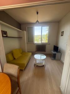 a living room with a yellow couch and a table at Le tourbillon nouveau in La Bourboule